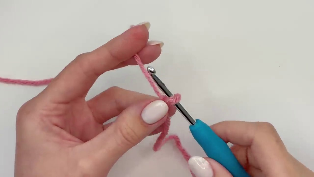 A close-up of the hook inserting into the first chain to join the ring with a slip stitch, forming a perfect, untwisted loop.