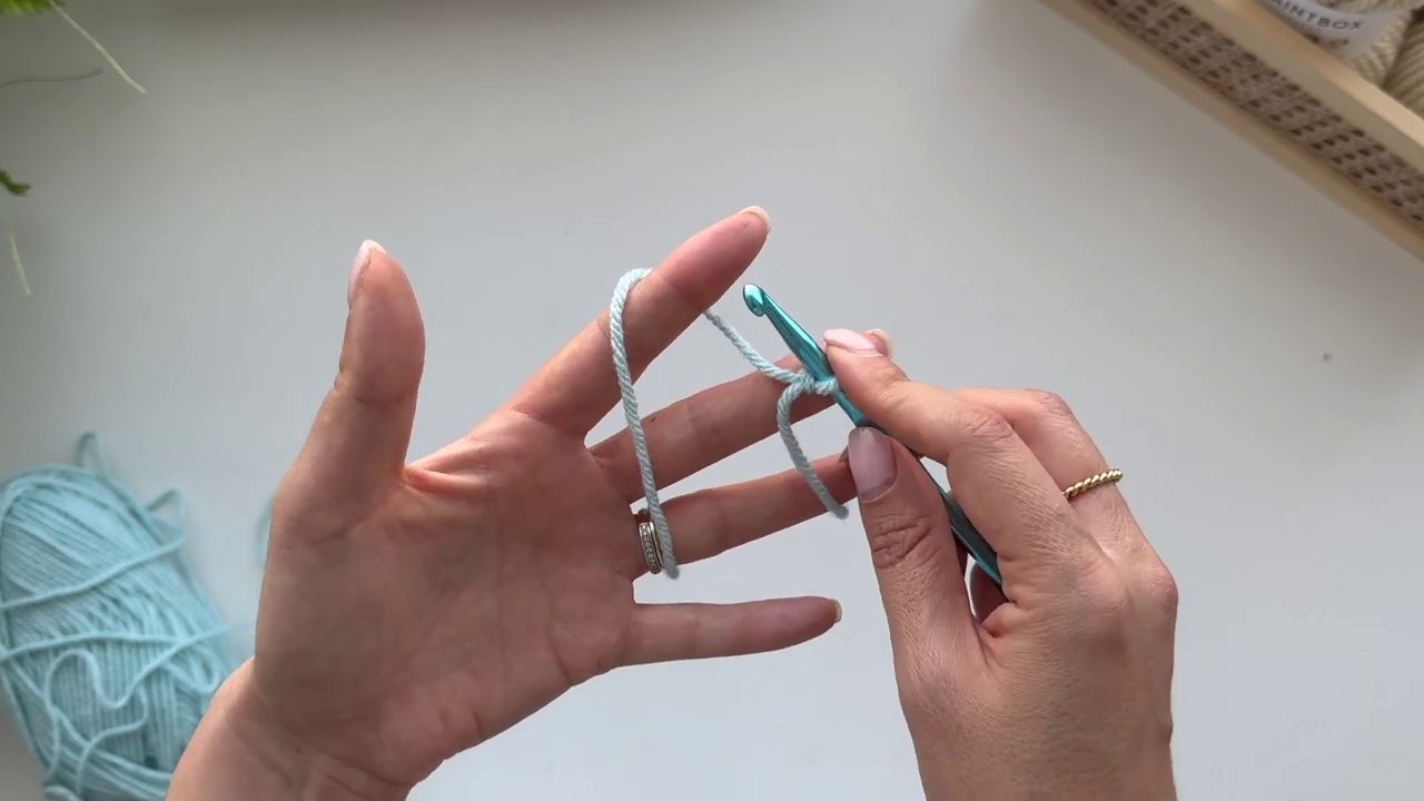 The hands demonstrate the necessary adjustment, releasing the pinched work to allow the yarn to feed freely.