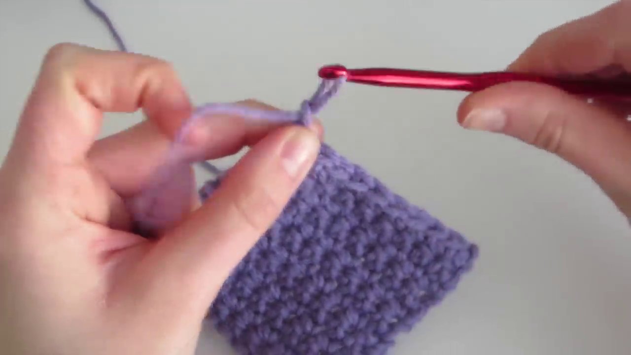 The final step of fastening off, pulling the cut yarn tail through the last loop on the hook.