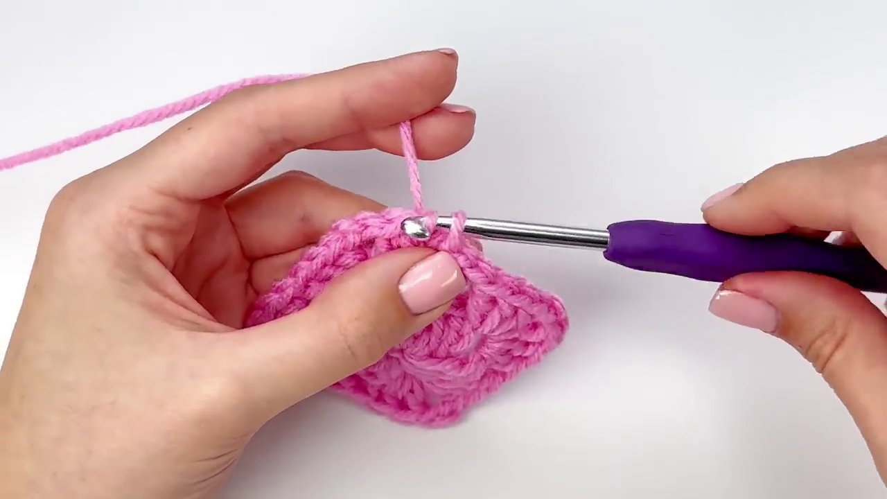 The final, completed granny square held up, showcasing its perfect square shape and textured pattern.