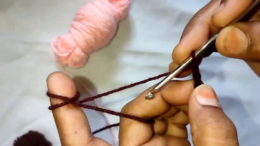Close-up of hands switching from pink to green yarn, with the hook poised to begin a new row.
