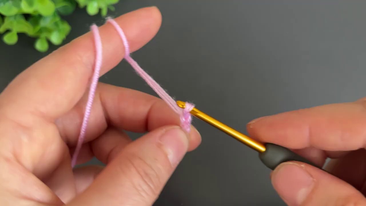 The formula "1dc+(2dc+2ch+2dc)+1dc" appears at the top of the frame as hands work the stitches.