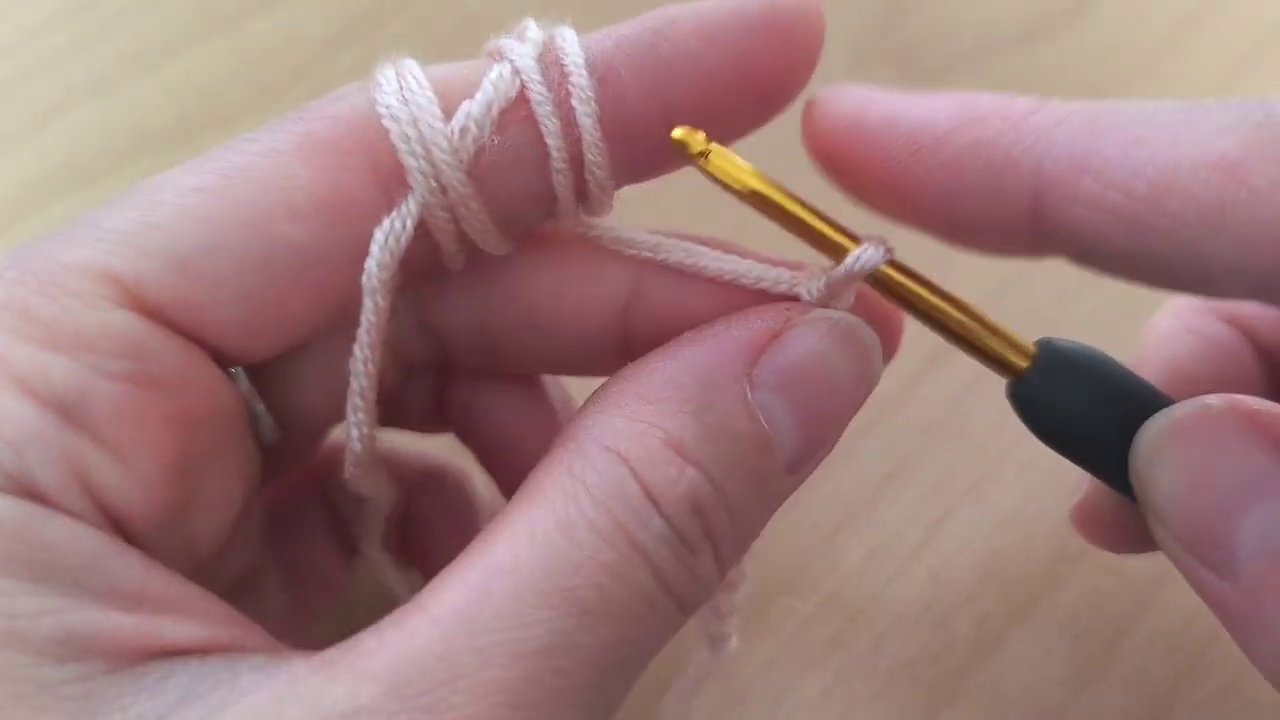 The left hand adjusts the yarn tension, fingers relaxed but in control.