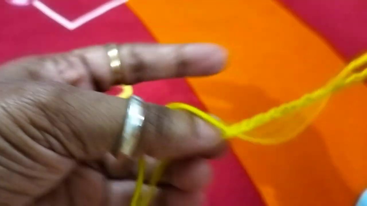 Close-up of the pink magic ring taking shape, with the crochet hook poised to pull through the first stitch.