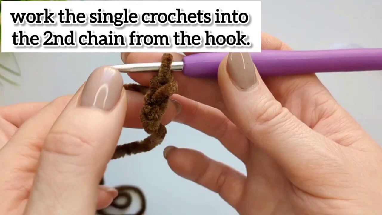Hands carefully passing a lighter near the cut end of a chenille yarn strand to seal it.