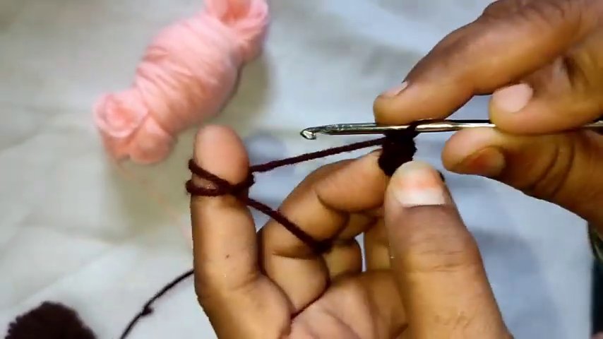 A completed section of green crochet stitches resting on a white surface, with the hook still inserted in the working loop.