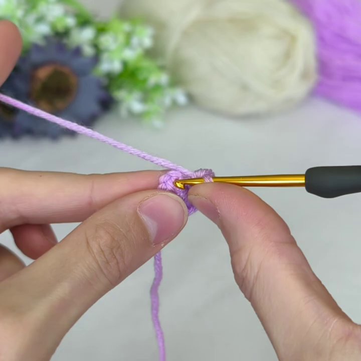 The white yarn is joined to the purple center, with the first white stitches forming a neat ring around the original motif.