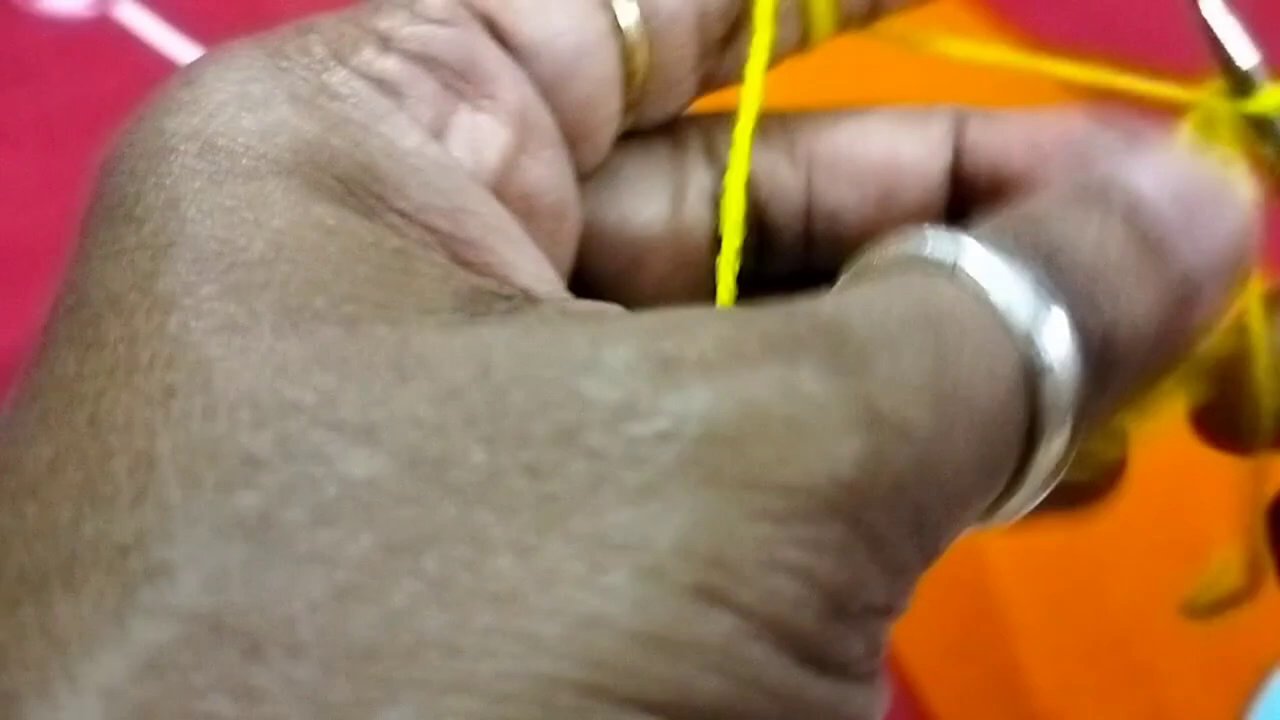 Hands working the yellow yarn into the pink base, showing the color change at the stitch level.