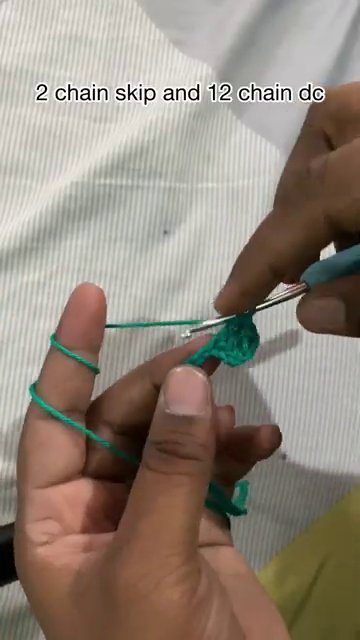 A hand demonstrating the yarn-over motion with the hook tip catching the strand.