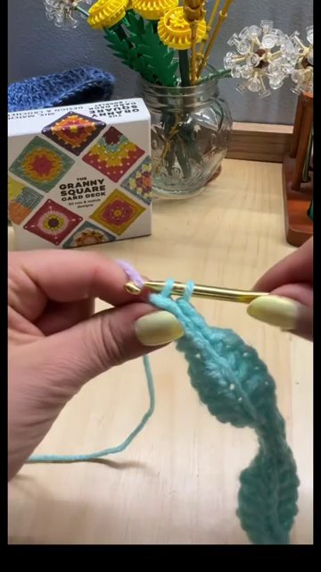 Two yarn colors joined at the edge of the work, with the old color looped loosely to the side ready to be picked up again.