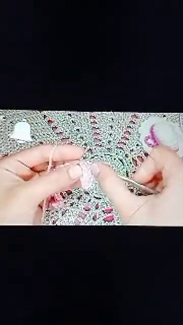 Hands adjust position slightly, revealing more of the completed crochet piece.
