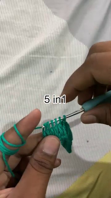A person gently pulling out a chain to restart, yarn loosely coiled on the table.