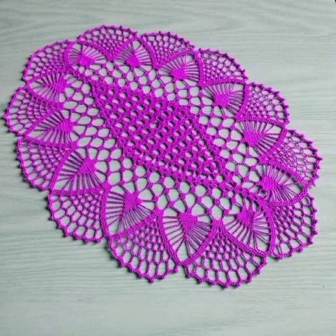 A finished crochet table runner laid flat on a white surface, showing the full pattern and fringe details.