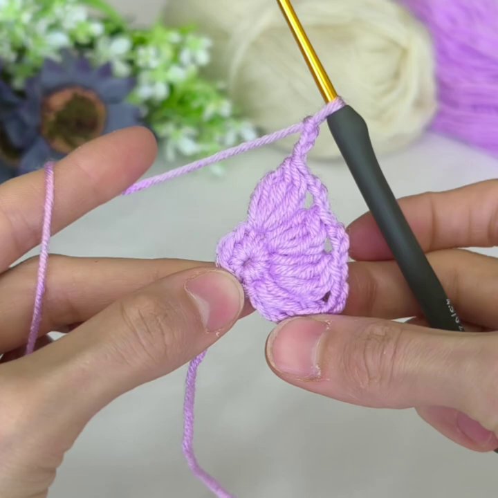 The completed motif, held in the maker’s hand, showing the clean two-tone design and even tension throughout.