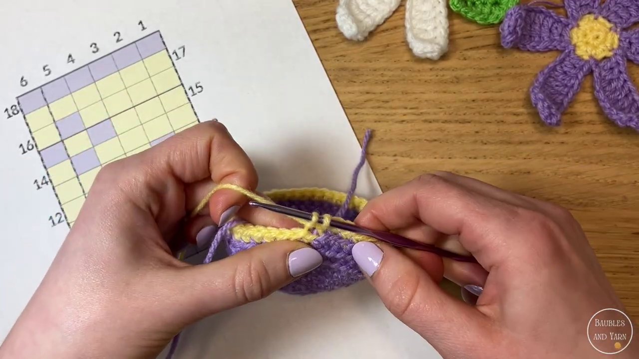 Carrying yarn across the back of the work, catching it with each stitch to maintain tension.