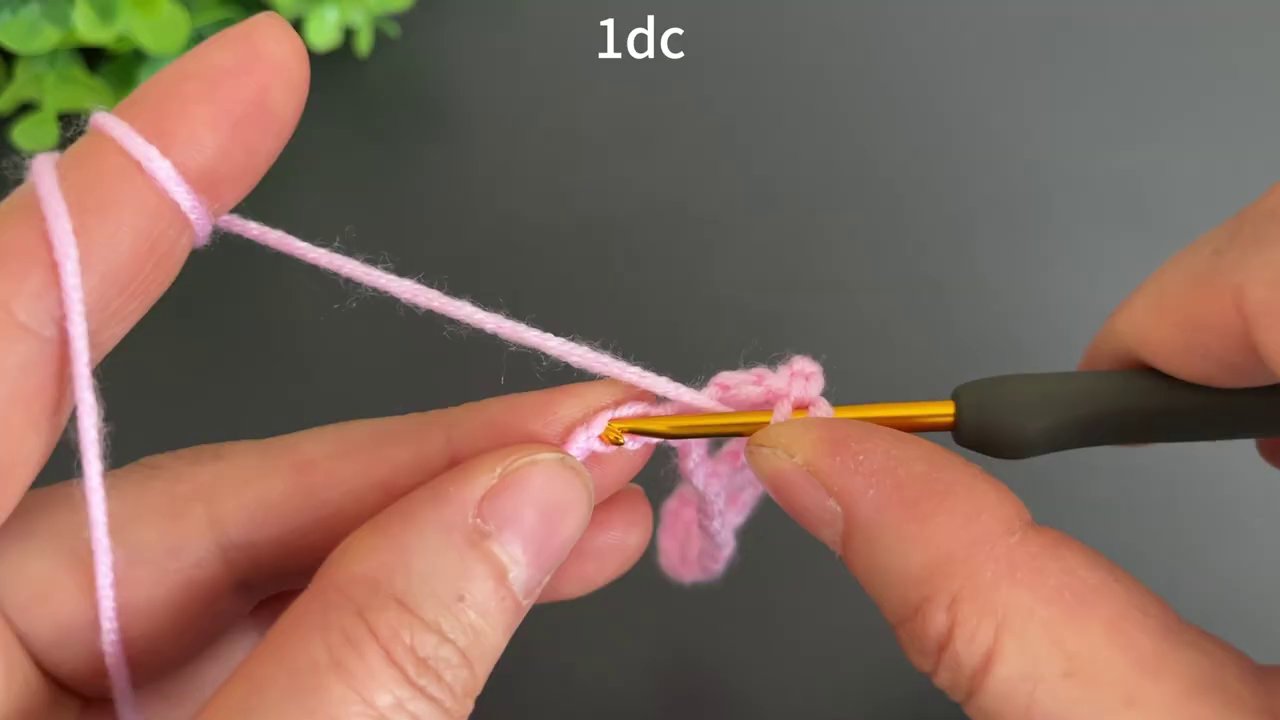The pink blanket grows longer, with several completed rows visible and the hook positioned for the next stitch.