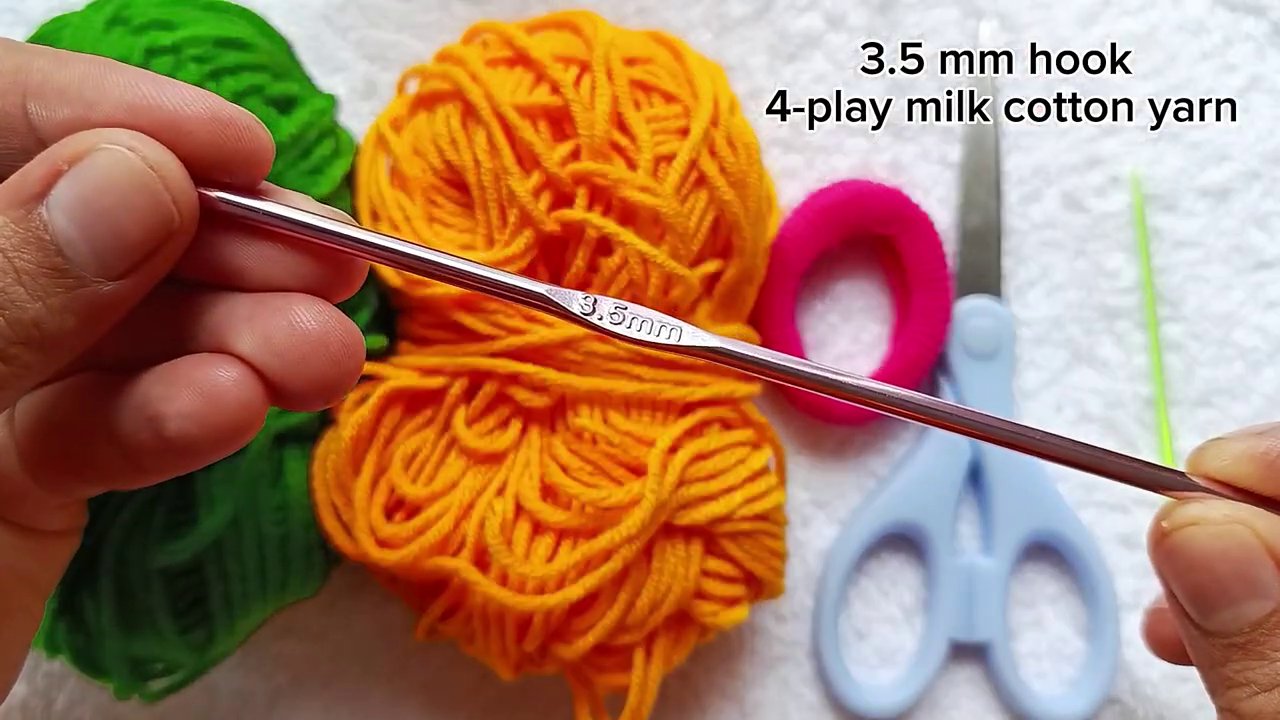 Your materials laid out: yarn, crochet hook, hair elastic, scissors, and a yarn needle.