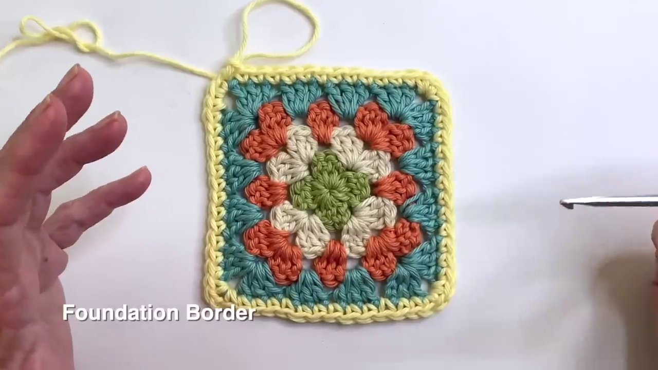 A crochet border being worked along the edge of a blanket, with the hook inserted into the side stitches.