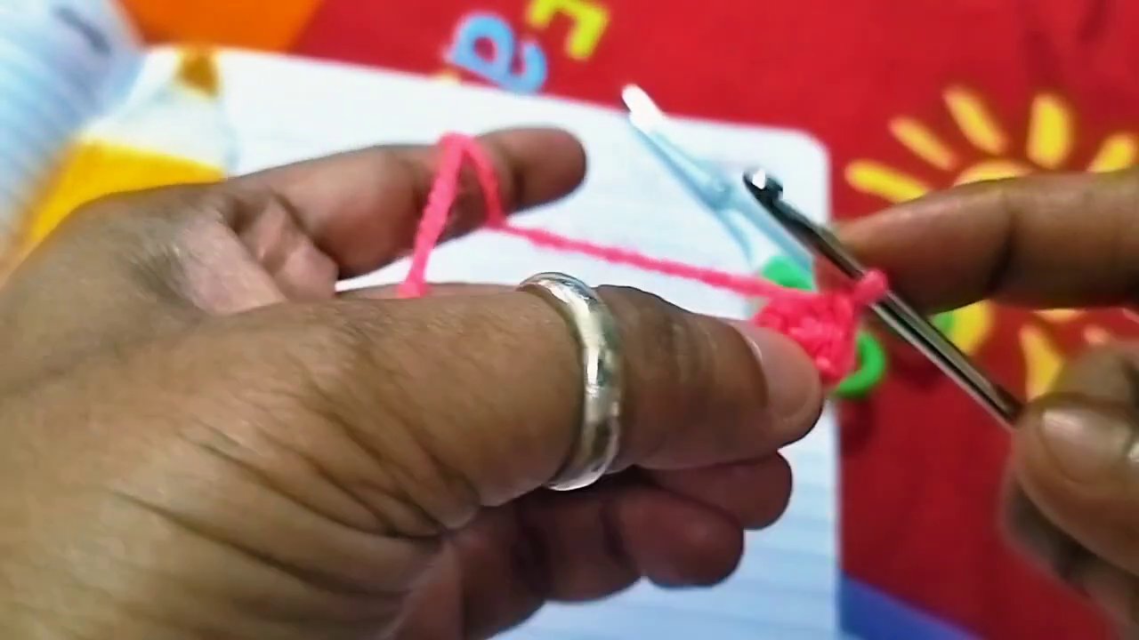Close-up of the crochet hook looping yarn to form the first chain stitches.