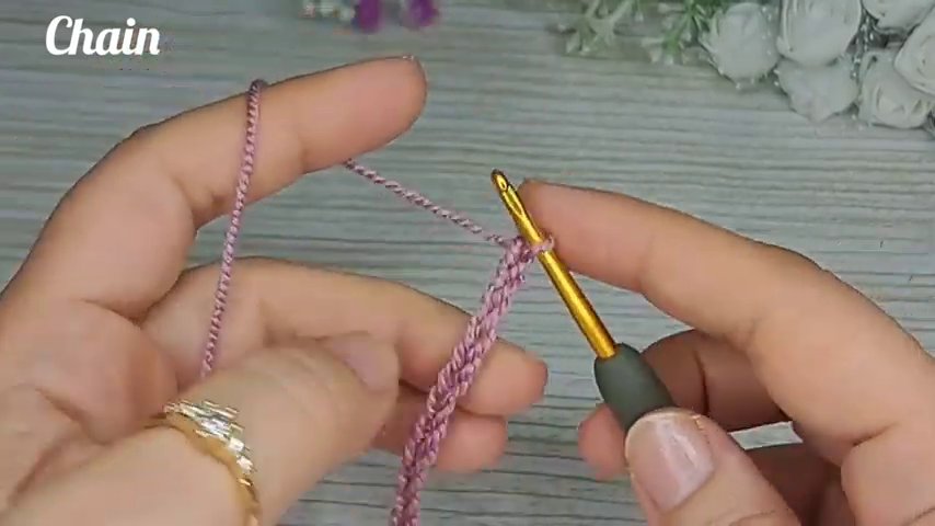 The hook is inserted under the back loop of a double crochet stitch, with the front loop visible and untouched.