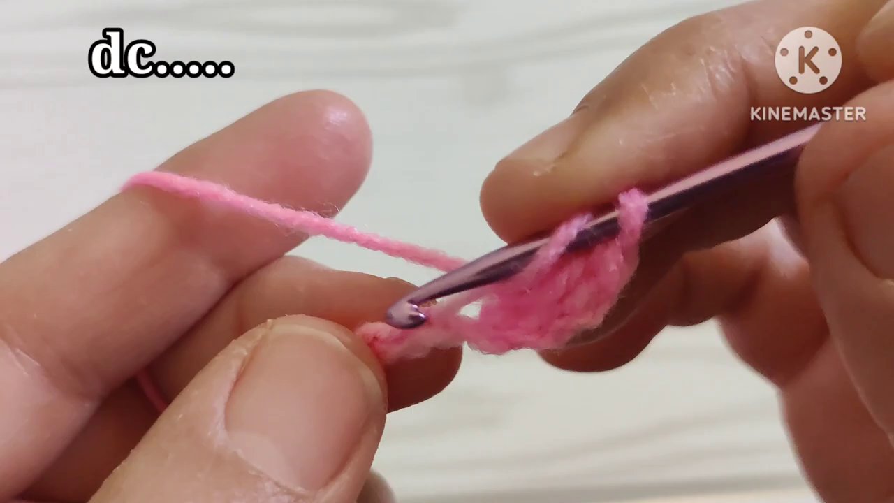 Close-up of the hook pulling through both loops to complete a single crochet stitch.