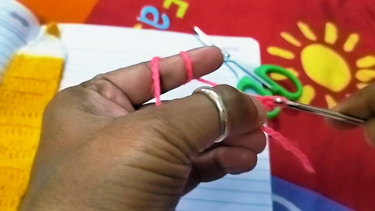 Hands switching from pink to white yarn mid-row, showing the color change technique.