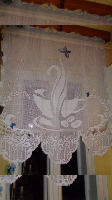 Close-up of a filet crochet curtain panel showing a floral pattern in the mesh grid.
