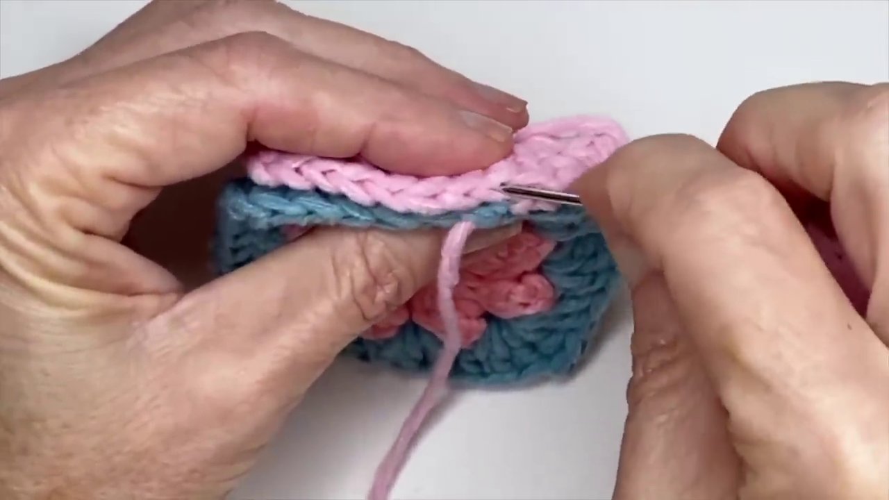 A magic knot being tied with two different colored yarns, showing the two knots sliding together.