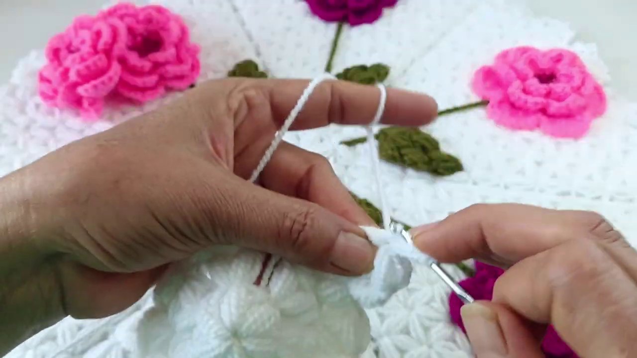 A crocheter's workspace with pattern printouts, yarn, hooks, and stitch markers organized on a wooden table.