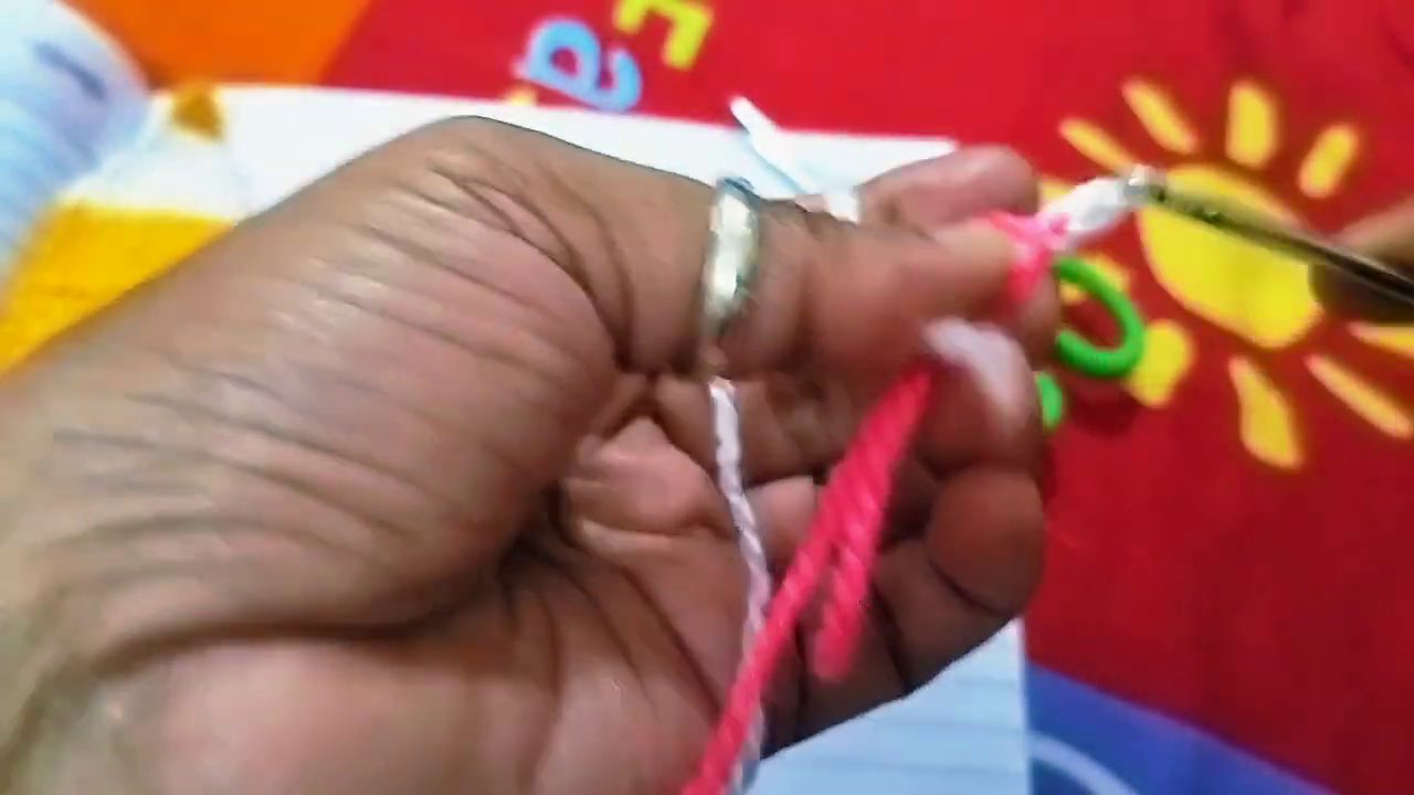 Hands tying the tassel onto the corner of the finished bookmark.
