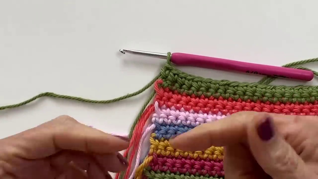 A hook inserted into the front loop and side bar of a stitch, ready to pull through a new color.