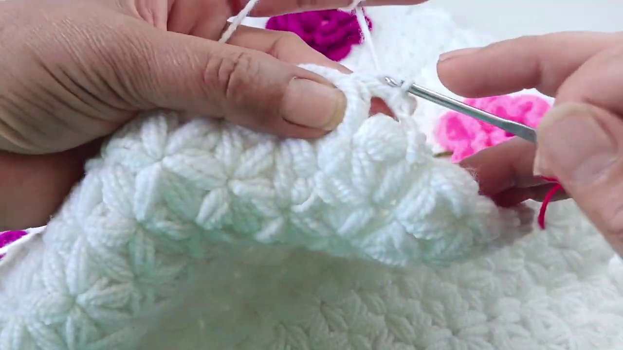Close-up of a crocheter's hands holding a partially finished amigurumi frog, showing the color changes and stitch details.