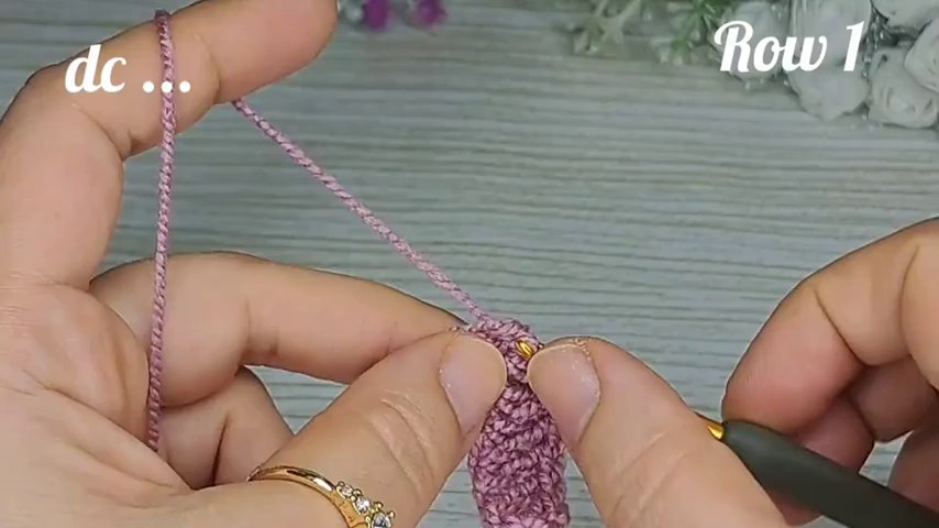 Close-up of the gold crochet hook and pink yarn, showing the ergonomic handle and smooth shaft.