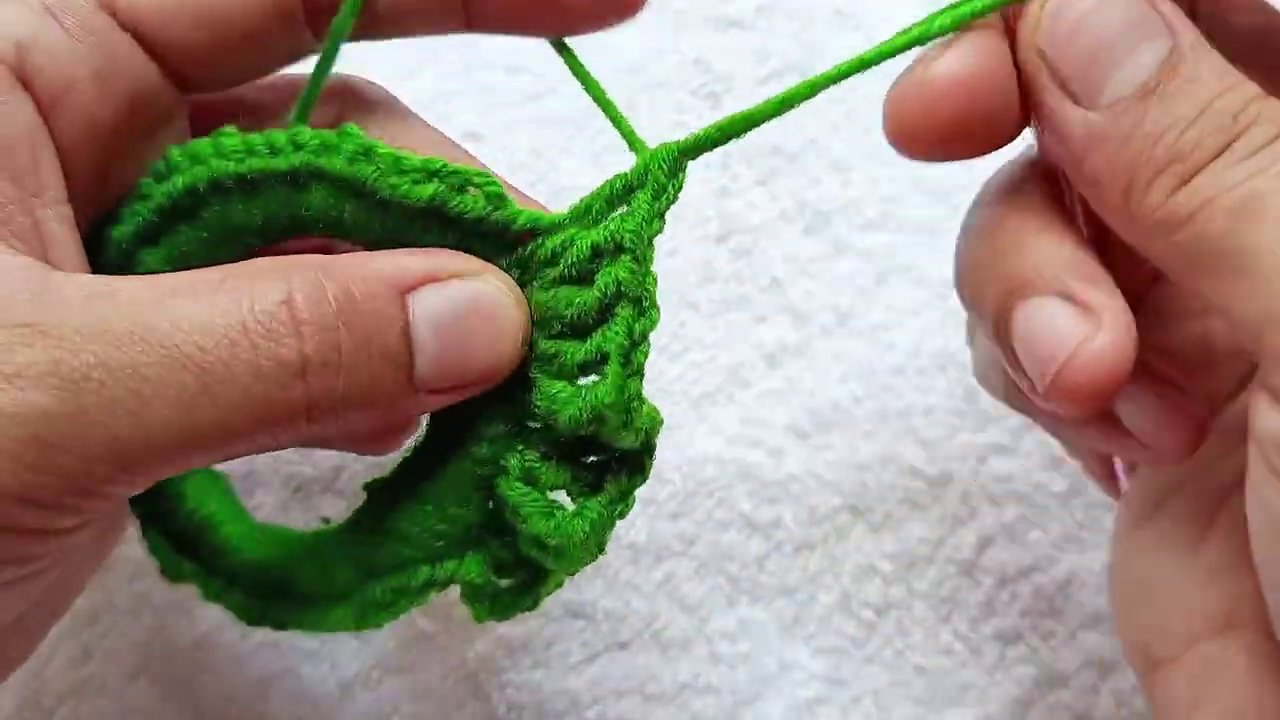 A finished scrunchie held in an open hand, showing the gathered ruffle texture against a plain background.