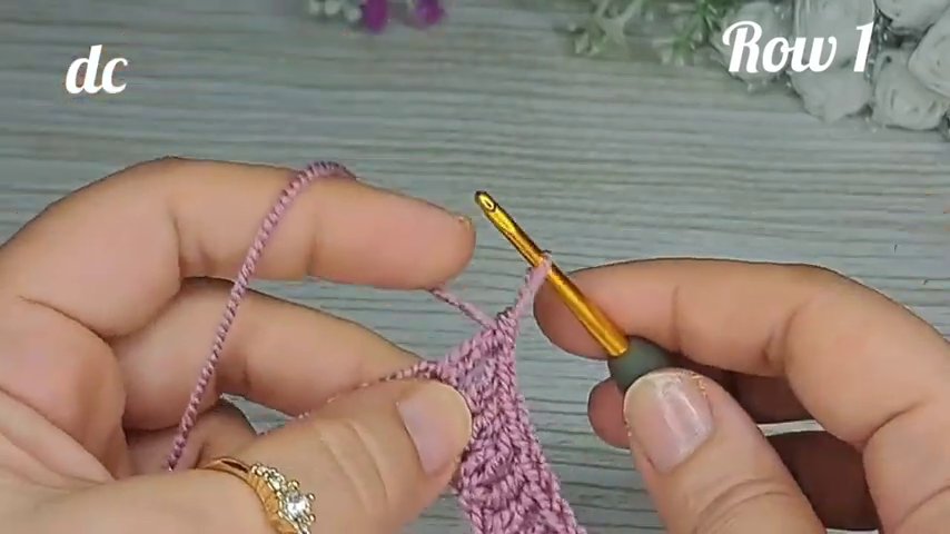The hands work the back loop double crochet stitch, with the fabric showing clear ridges from the previous rows.