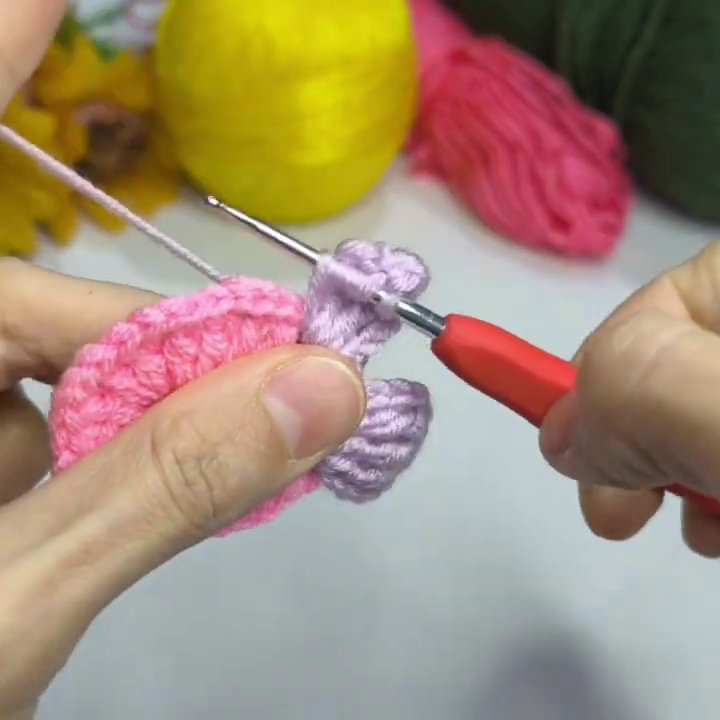 The finished flower motif photographed from above on the white table, with yarn balls and hook visible in the background.