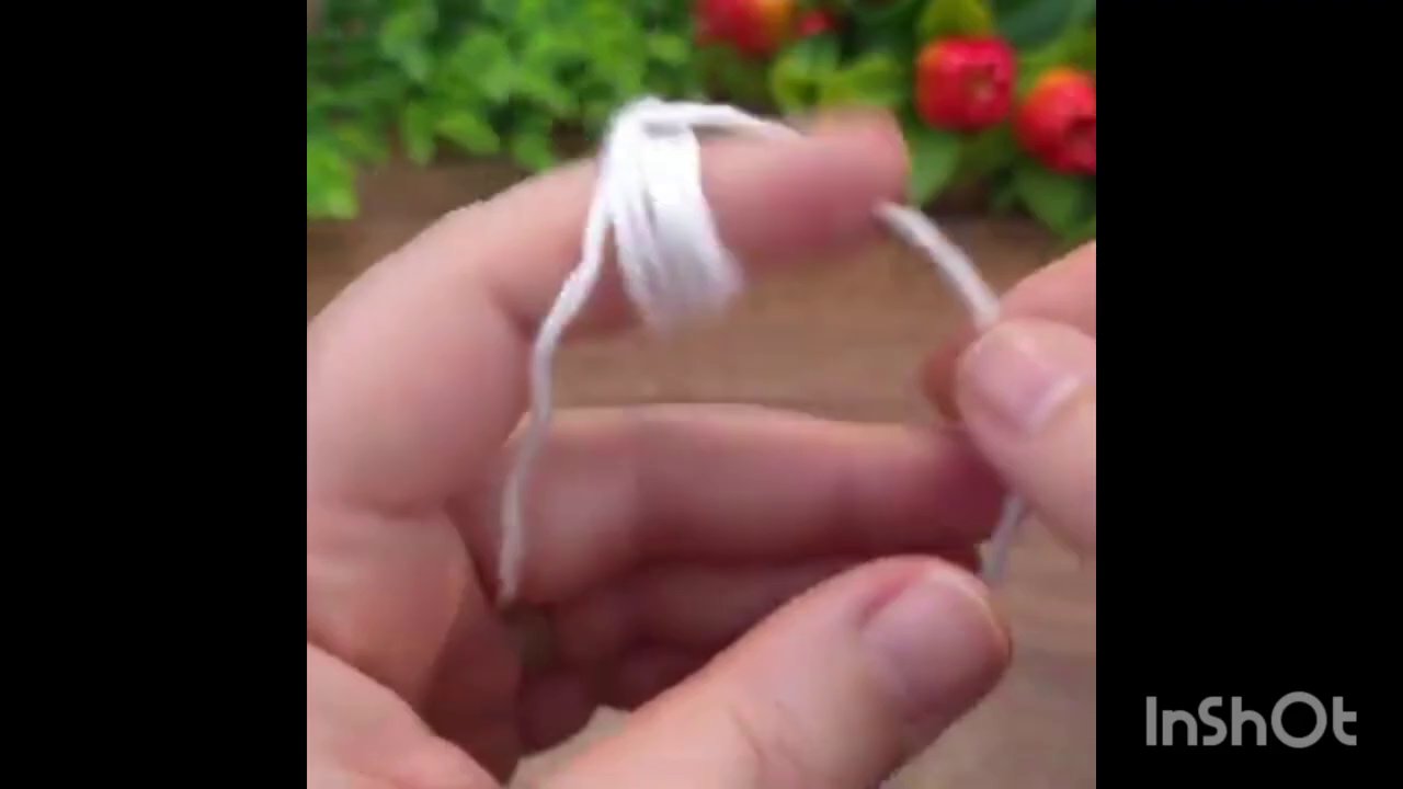 Hands weaving green yarn into the existing white crochet work, with the hook in the right hand.