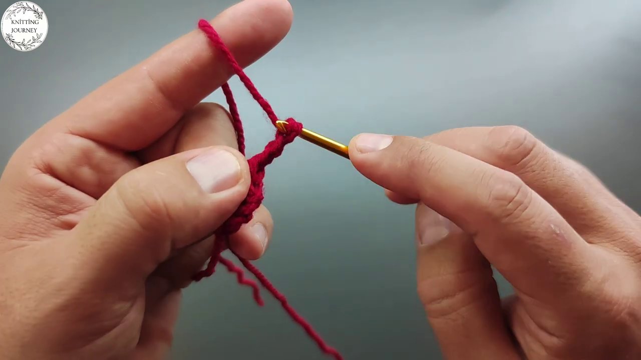 Close-up of the crochet hook inserted into a yarn loop, with fingers holding tension steady.