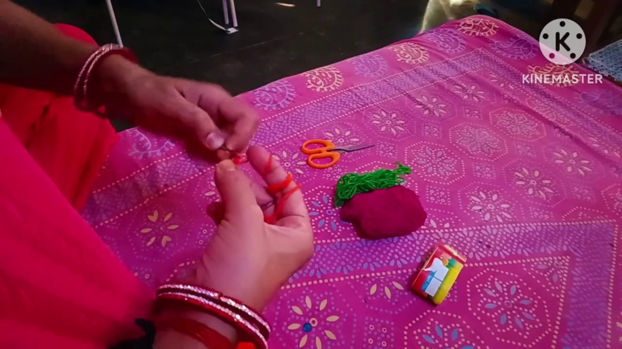 The crochet hook and green yarn resting on the fabric, with orange scissors and a small box beside them.