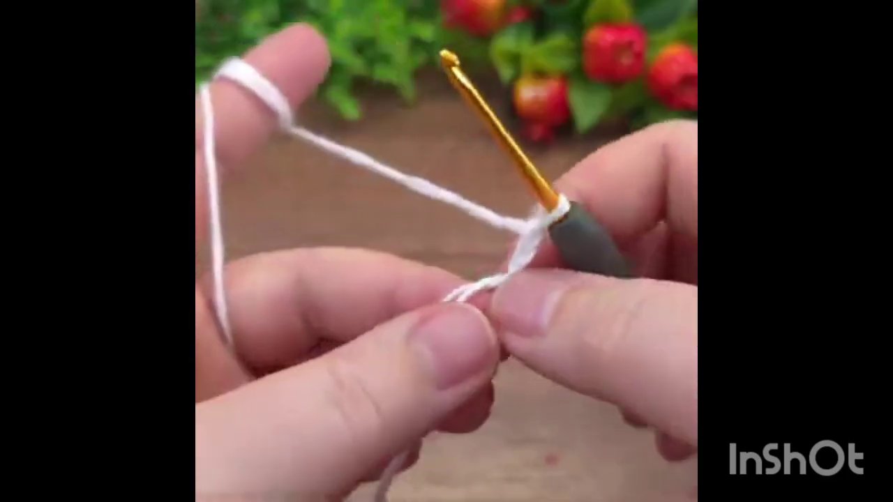 Hands adding red yarn to the existing white and green crochet piece, with the hook in the right hand.