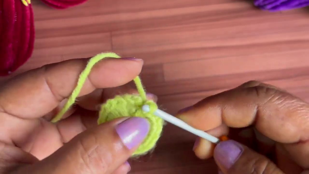 White stitches form a circular base, preparing the flower for its orange petal layer.