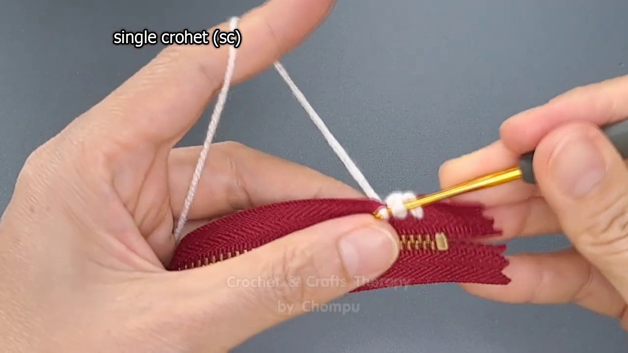 Hands working half double crochet stitches, with the textured pattern becoming visible.