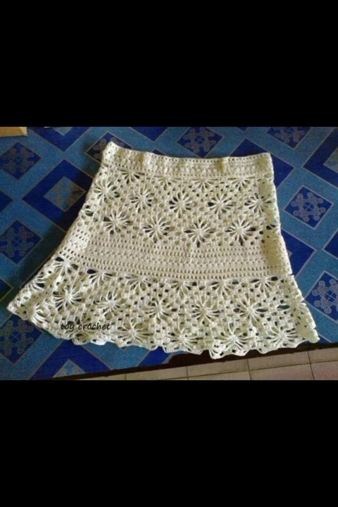 A crocheted shawl with a repeating shell stitch pattern, draped on a mannequin.