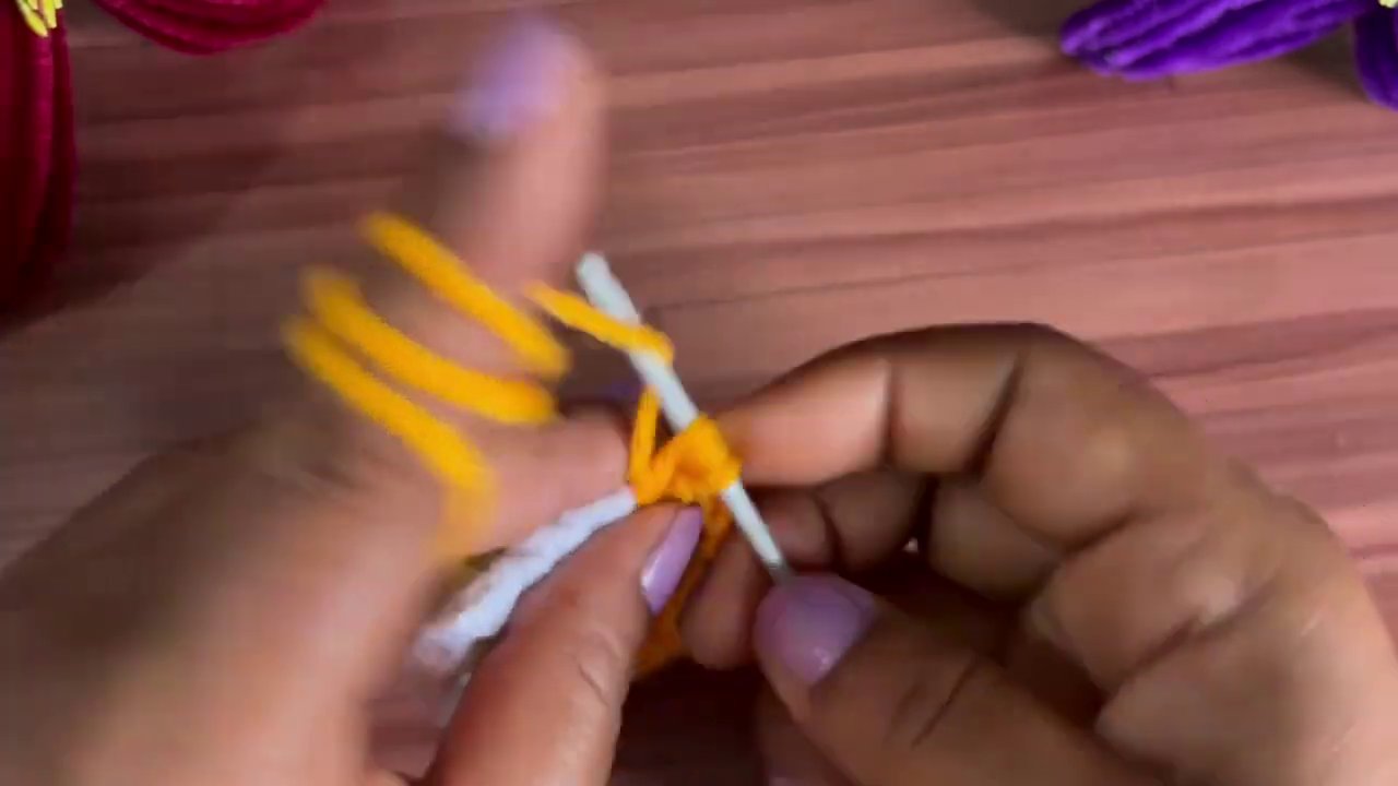 The orange yarn is carefully worked into the flower’s center, adding texture and definition.