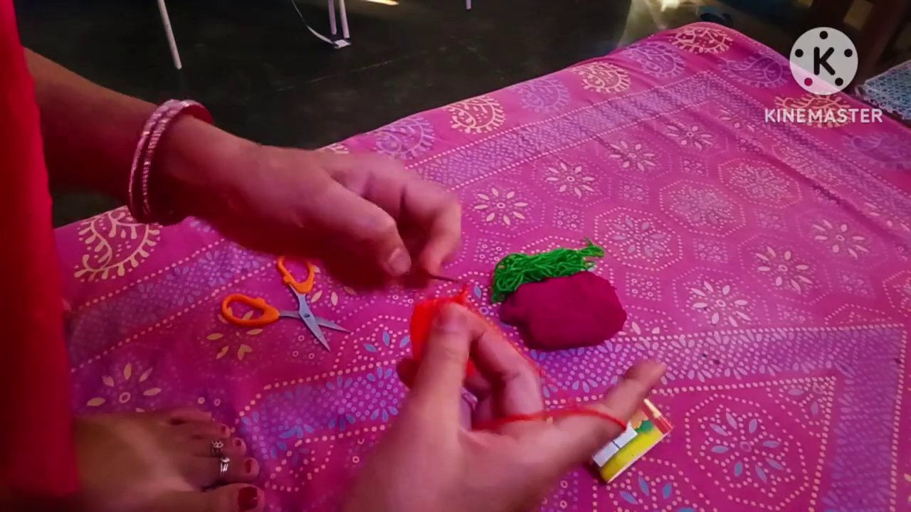 A completed crochet leaf held between fingers, with the yarn tail visible before being woven in.