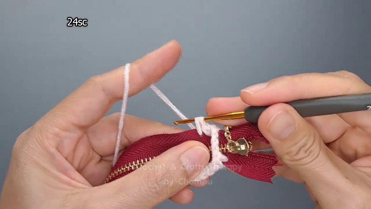 Yarn needle weaving a tail into the interior of the finished purse.