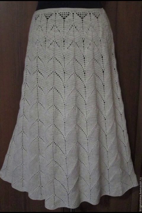 A finished crochet blanket folded neatly on a wooden chair, with natural light streaming in from a window.