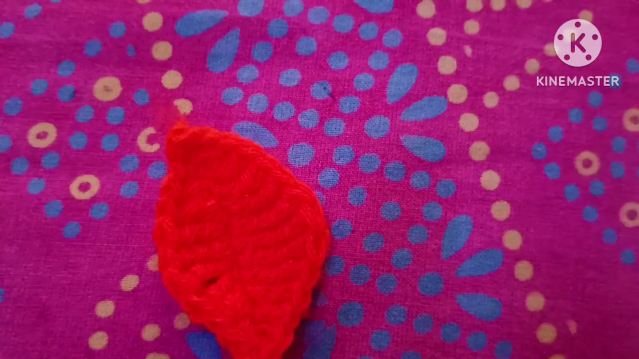 The crocheter’s hands holding the finished leaf next to the original ball of yarn and hook, showing the complete process from start to finish.